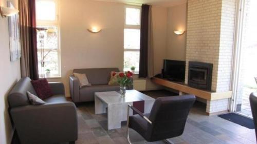 sala de estar con sofá y chimenea en Bungalows für vier Personen, direkt am Strandbad gelegen, en Oostrum