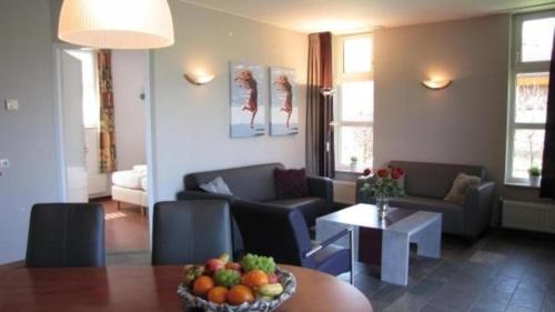 sala de estar con sofá y mesa con un bol de fruta en Bungalows für vier Personen, direkt am Strandbad gelegen, en Oostrum