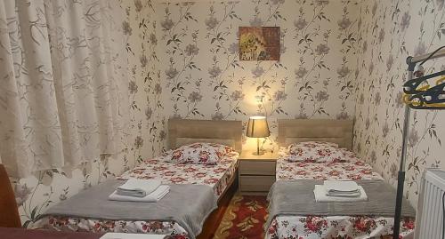two twin beds in a room with wallpaper at Cozy House II in Tbilisi City