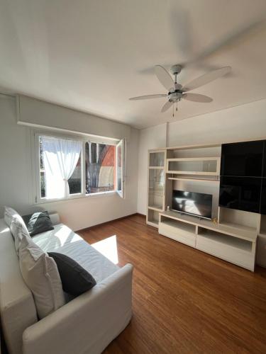 a living room with a white couch and a flat screen tv at Un balcone sul mare in Sori