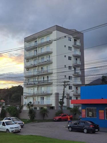 a large apartment building with cars parked in a parking lot at Ap frente para o mar in Caraguatatuba