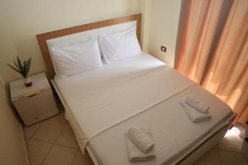 una camera da letto con un letto bianco con due cuscini sopra di Gusto Hotel a Ksamil