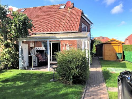 une petite maison en briques avec un toit rouge dans l'établissement Ferienhaus Huus Wattenmeer in Nessmersiel mit Garten, Terrasse, Sauna, Räder, und Grill, à Dornum
