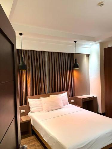 - une chambre avec un grand lit blanc et deux lumières dans l'établissement Monarch Suites at Padgett Cebu w/ pool near Ayala, à Cebu