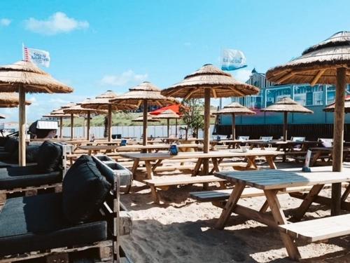 a group of picnic tables with umbrellas on a beach at Bundi Beach in Egmond aan Zee