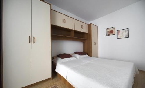 a bedroom with a white bed and a white cabinet at Apartmani Nika Marangun in Dubrovnik