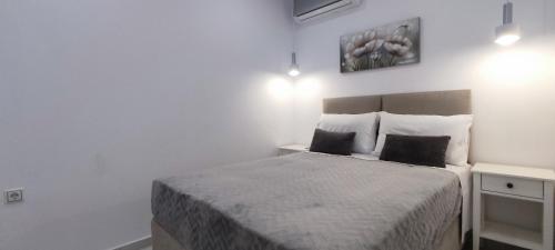 a white bedroom with a bed with two pillows at Lusso di Campiello in Corfu Town