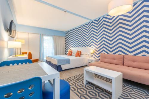 Terrace Mar Suite Hotel في فونشال: غرفة في الفندق مع أريكة وسرير