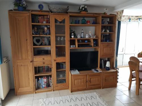 a wooden entertainment center with a television in a living room at Ferienhaus in Neßmersiel mit Großer Terrasse in Dornum