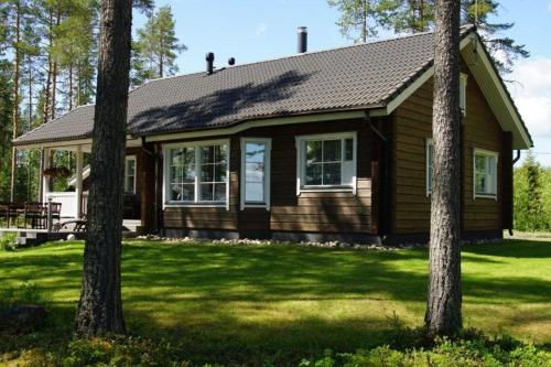 a small cabin with trees in front of it at Hochwertiges Ferienhaus mit Sauna sowie Holzterrasse und Garten am See in Sotkamo