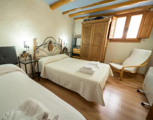 um quarto com 2 camas e uma cadeira em Apartamentos la Rambla Callizo em Montalbán