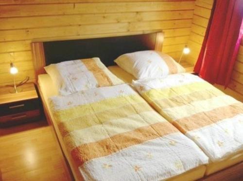 2 Betten in einem Schlafzimmer mit einer Holzwand in der Unterkunft Harzer Blockhaus III in Bad Sachsa