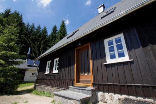 a black house with a wooden door and stairs at Appartement in Klingenthal mit Terrasse, Garten und Grill in Klingenthal