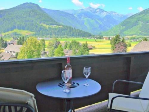 a table with two wine glasses on a balcony with mountains at Wohl eingerichtete Wohnung mit eigenem Balkon und Panoramablick in Sankt Michael im Lungau
