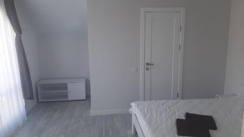 een witte slaapkamer met een bed en een kast bij Sofi in Yablunytsia