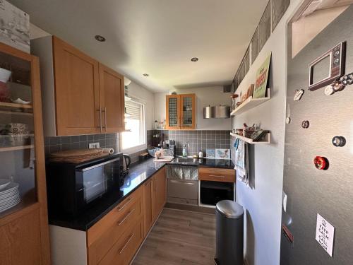 - une petite cuisine avec des placards en bois et un four micro-ondes dans l'établissement L'Hay-les-Roses proche RER Paris, à LʼHay-les-Roses