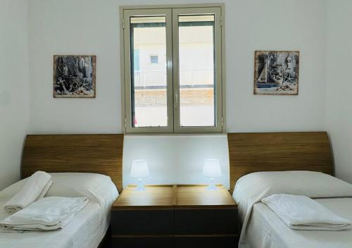 two twin beds in a room with a window at MareVivo Marzamemi in Marzamemi