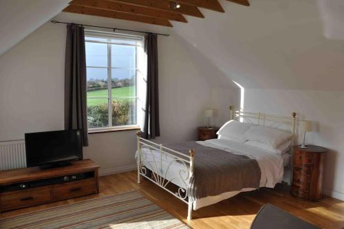 1 dormitorio con 1 cama, TV y ventana en Bed@Byways, Holton, en Wincanton