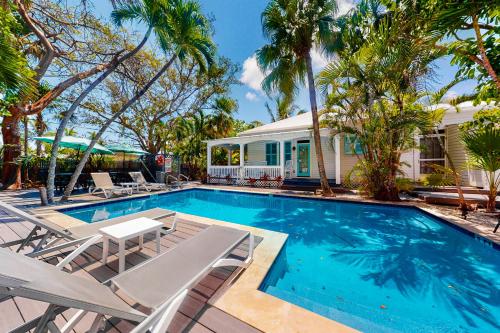 einen Pool mit Stühlen und ein Haus in der Unterkunft Papa's Hideaway in Key West