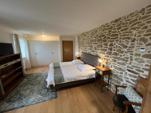 Un dormitorio con una pared de piedra y una cama en Domaine de la Calamande, en Grillon