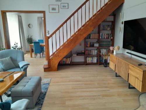 a living room with a staircase with a couch and a tv at Ferienhaus in Kolberg mit Grill und Garten in Kołobrzeg