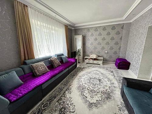 a living room with a purple couch and a window at Altan Hostel Osh in Osh