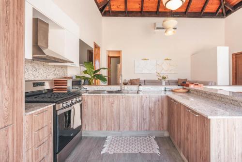 プンタ・カナにあるTropical villa with picuzzi at Green Village BCAの木製のキャビネットとコンロ付きオーブンを備えたキッチン