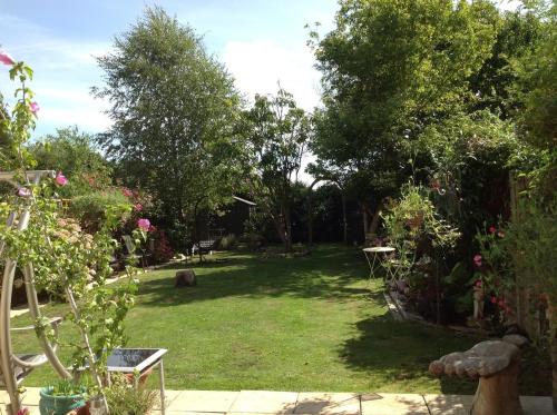 einen Garten mit Bäumen und einer Liegewiese mit einer Bank in der Unterkunft Shepperton Guesthouse in Shepperton