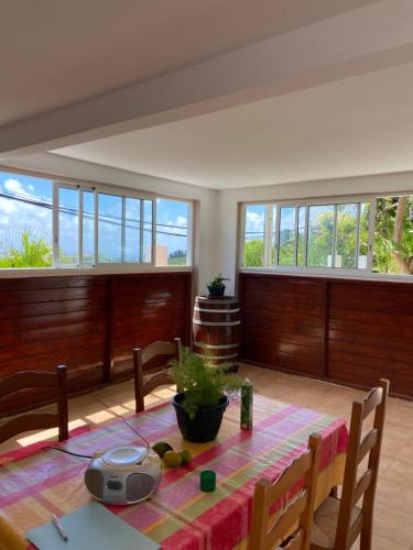 a dining room with a table and some windows at Maison SOLEIL - VAUCLIN in Le Vauclin