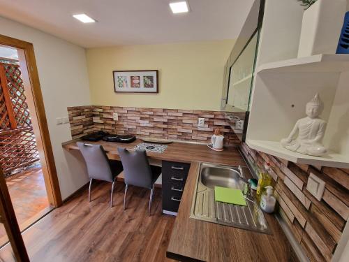 a kitchen with a counter with chairs and a sink at Stela Apartman Štúrovo in Štúrovo