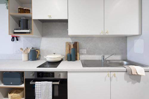 una cocina con armarios blancos y fregadero en Keel House refurbished Studios, en Edimburgo