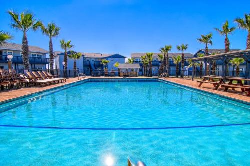 a large swimming pool with chairs and palm trees at Captain Quarter's 1 bedrm unit at Sea Isle Village in Port Aransas