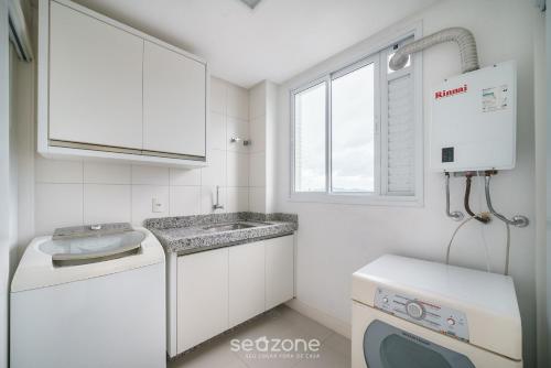 a white kitchen with a sink and a washing machine at Apto Vista Mar cond. c/ piscina e churrasq VCE1102 in Piçarras