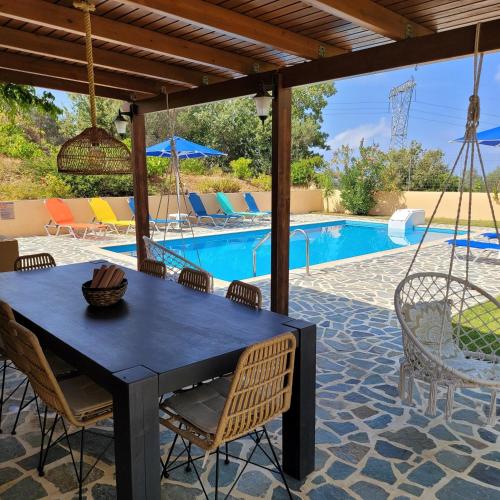 a patio with a table and chairs and a pool at Villa Farangi freistehend mit Pool und herrlichem Blick auf die Hügel und das Mittelmeer in Somatás