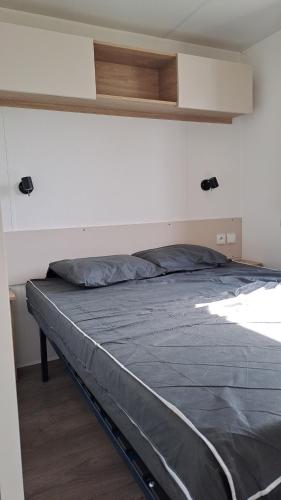 a bed in a room with a white wall at Les sables du midi in Valras-Plage
