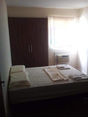 Cama en habitación con ventana y toallas en Conforto e Localização, en Recife