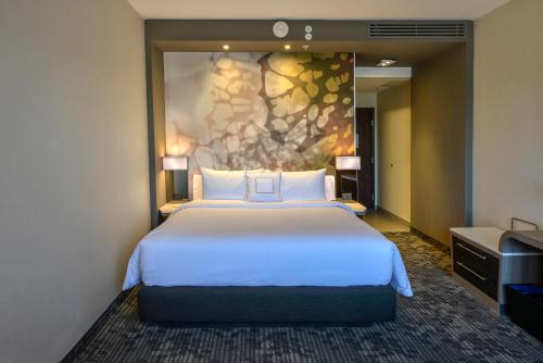 a bedroom with a large bed with a painting on the wall at Courtyard by Marriott San Luis Potosi, Los Lagos in San Luis Potos&iacute;
