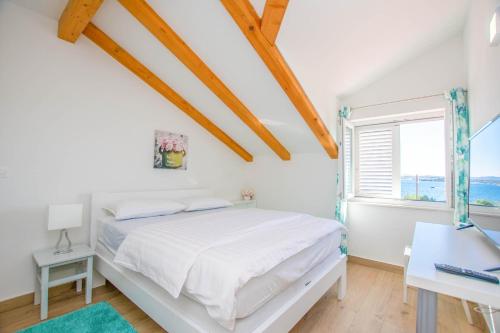 a white bedroom with a bed and a window at House Villa Verdi in Tkon
