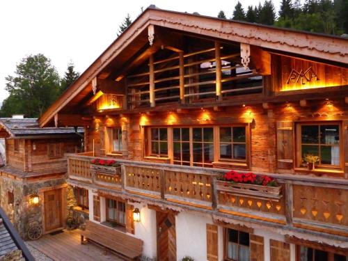 ein großes Holzhaus mit Blumen auf dem Balkon in der Unterkunft Ferienhaus für zehn Erwachsene und zwei Kinder mit Sauna und Kamin in Flachau