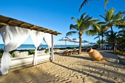 a building on a beach with palm trees and the ocean at Hotel e Resort Villas de Trancoso in Trancoso