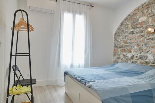 une chambre avec un lit et un mur en pierre dans l'établissement Ancien conservatoire, à Sète