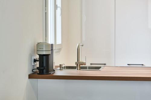 - une cuisine avec un évier et une cafetière sur un comptoir dans l'établissement Ancien conservatoire, à Sète