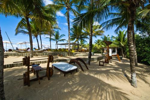 a park on the beach with chairs and palm trees at Hotel e Resort Villas de Trancoso in Trancoso