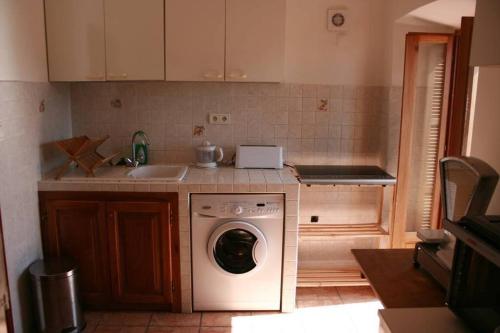 une cuisine avec une machine à laver et un évier dans l'établissement Charme du village-Plage à 10mn, à Corbara