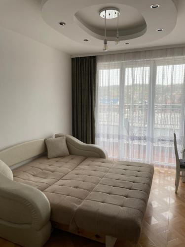 a bedroom with a couch and a large window at Apartman Dragovic in Kuršumlija