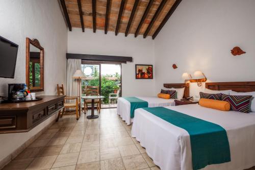 a hotel room with two beds and a television at Hacienda Buenaventura Hotel & Mexican Charm - All Inclusive in Puerto Vallarta
