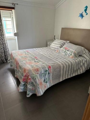 ein Bett mit einer Decke in einem Schlafzimmer in der Unterkunft Biá's House in Nazaré