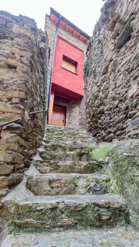 a red door on a stone building with stairs at Cal cavalé in Vall de Castellbò