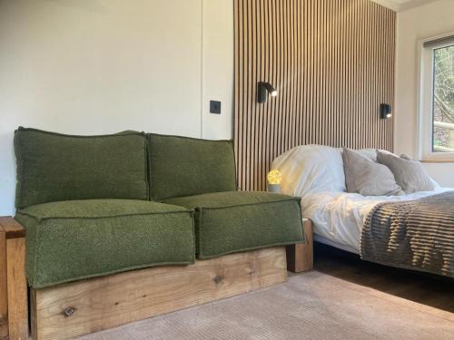 a bedroom with a green couch next to a bed at The Cabin in the Woods in Romsey