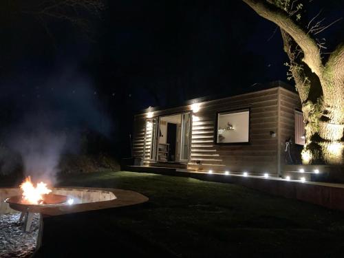 a fire pit in front of a log cabin at night at The Cabin in the Woods in Romsey
